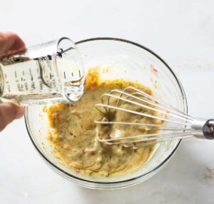 Oil being whisked into dill honey mustard sauce.
