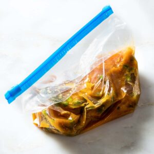 Chicken breast with pineapple marinade in a plastic bag.