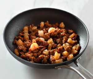 Cooked shrimp and chorizo in a pan.