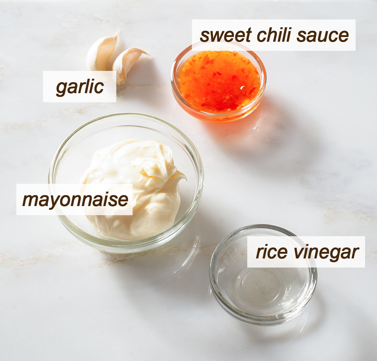 Garlic, mayonnaise, rice vinegar and sweet chili sauce in bowls.