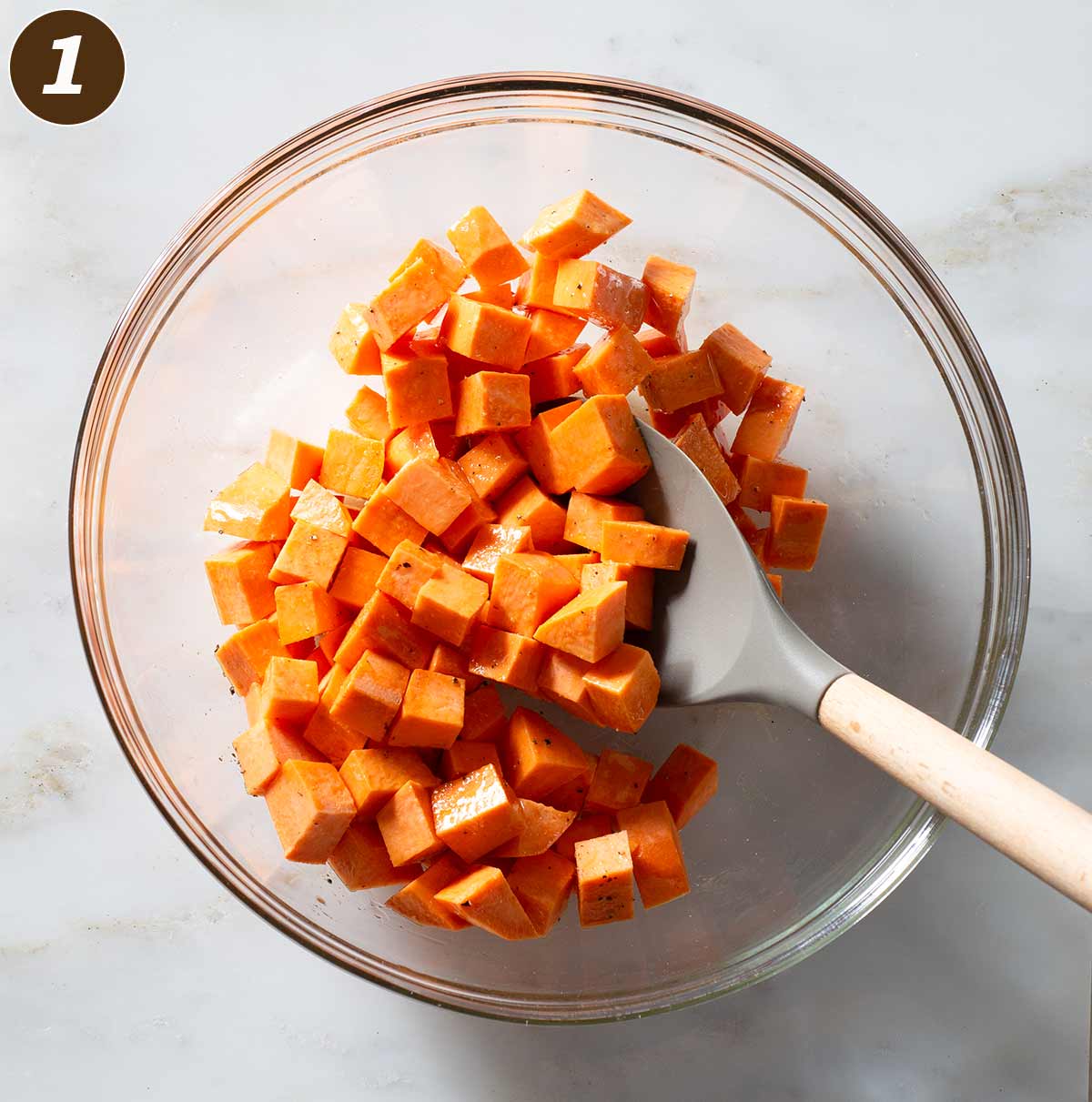 Raw sweet potato cubes being stirred in a bowl.