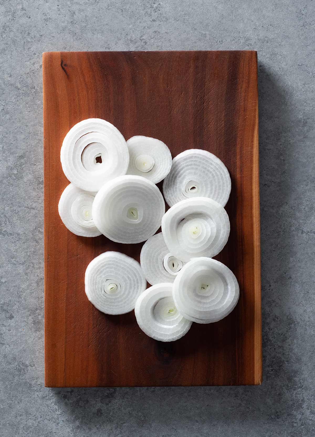 Onion rings on a wooden cutting board.