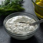 Sour cream tartar sauce in a glass bowl with a small spoon.