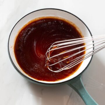 Bbq sauce being whisked in a saucepan.