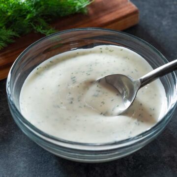 Buttermilk dill sauce in a bowl with a spoon.