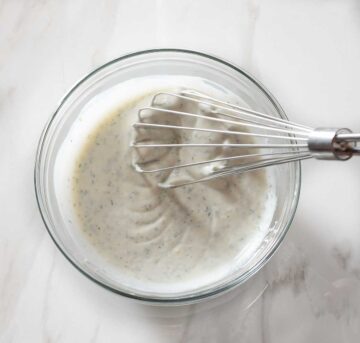 Buttermilk sauce being whisked in a bowl.