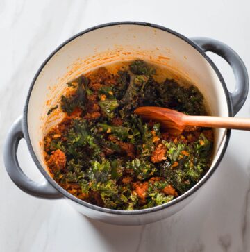 Cooked chorizo and vegetables being stirred in a Dutch oven.