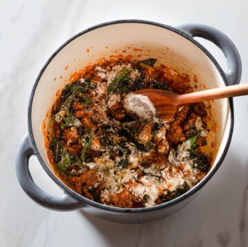 Chorizo, vegetables and flour being stirred in a Dutch oven.