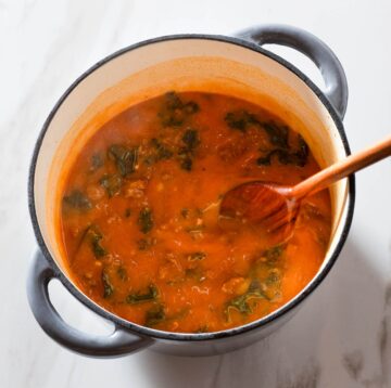 Soup being stirred in a Dutch oven.