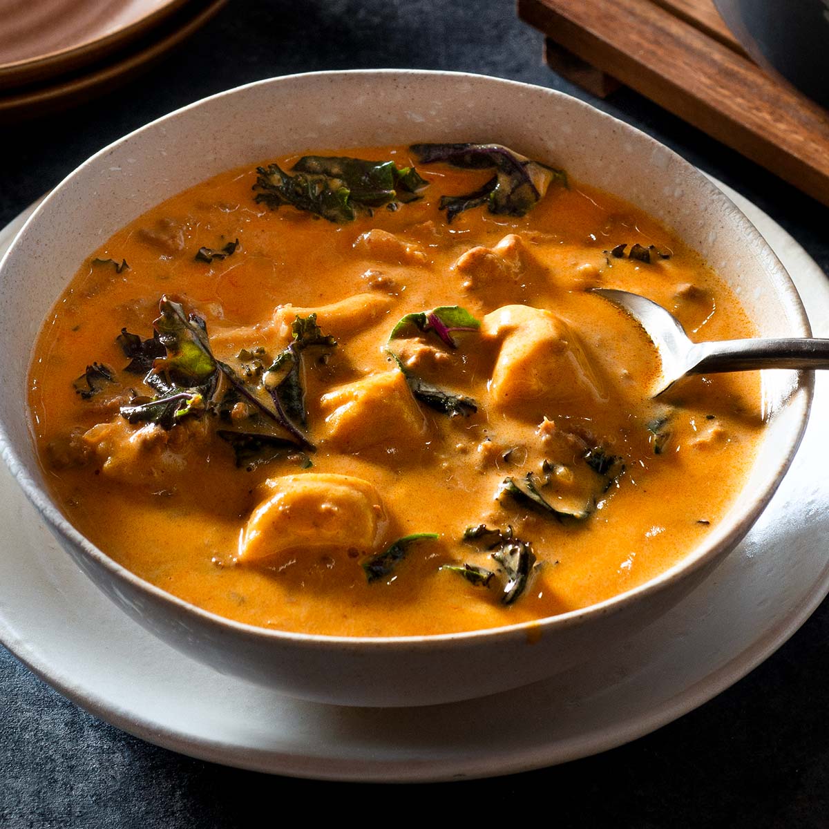 Bowl of creamy chorizo soup with a spoon.