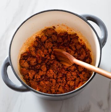 Cooked chorizo in a Dutch oven with a spoon.