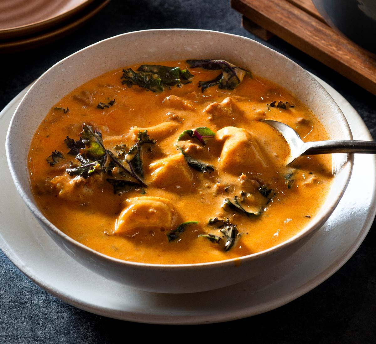 Bowl of creamy chorizo soup with a spoon.