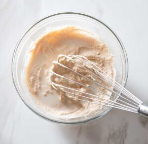Milk and sauce being whisked in a bowl.