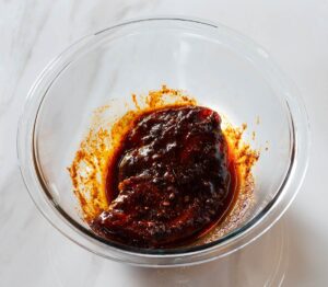 Chicken in ancho marinade in a bowl.