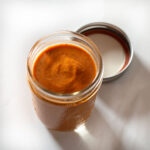 Creamy red enchilada sauce in a glass jar.