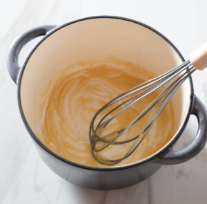 Roux being whisked in a pot.