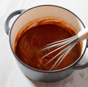 Enchilada sauce being whisked in a pot.