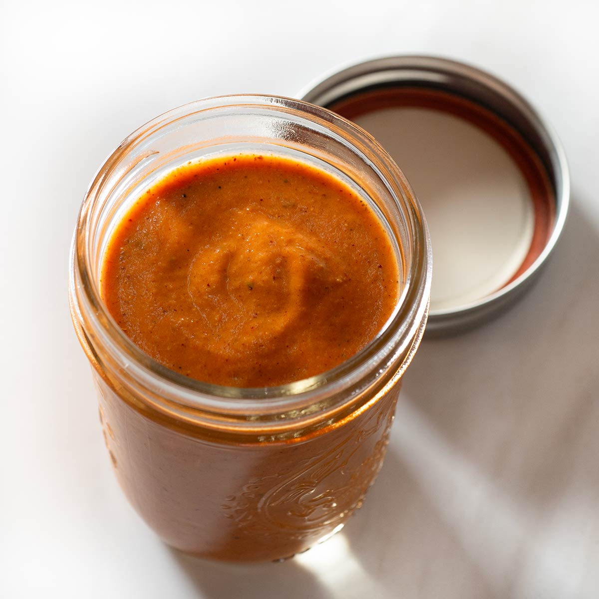 Creamy red enchilada sauce in a glass jar.