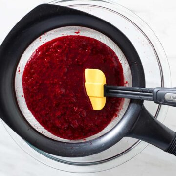 Raspberry sauce in a sieve.