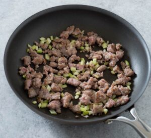 Sausage and celery in a skillet.