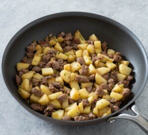 Sausage, celery and apple in a skillet.