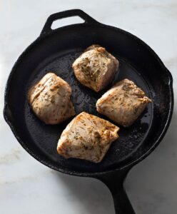 Seared pork tenderloin in a cast iron pan.