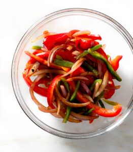 Charred peppers and onions in a bowl.