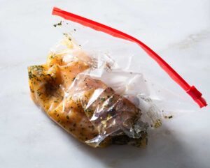 Chicken breast with marinade in a plastic bag.