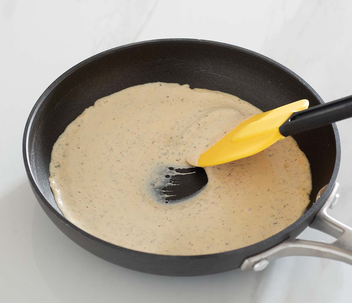 Cream sauce in a pan with a spatula.
