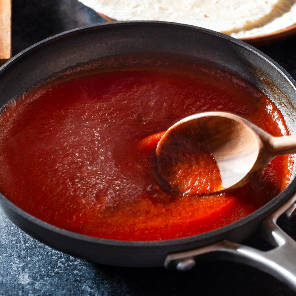 Chipotle enchilada sauce being stirred in a pan.