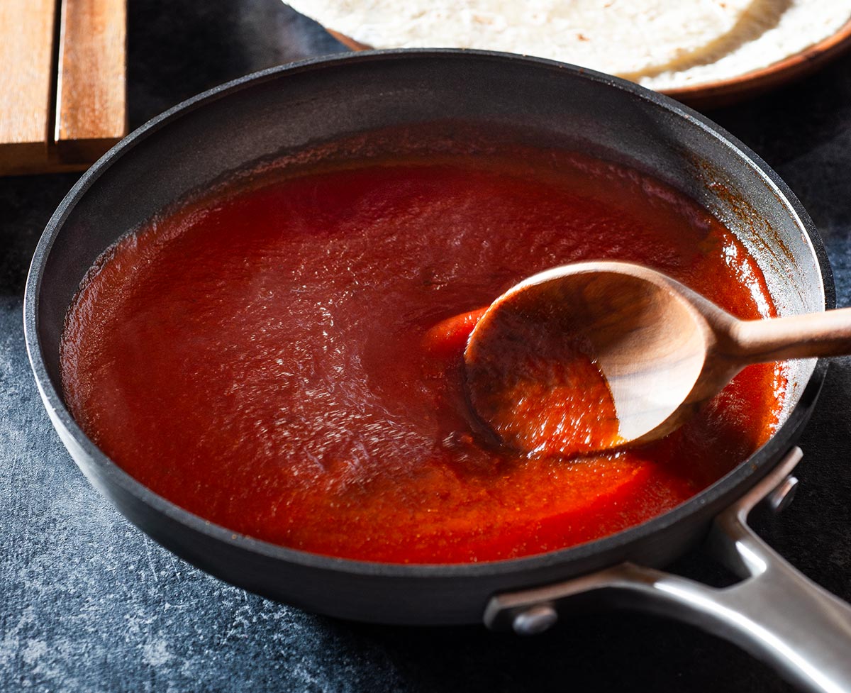 Chipotle enchilada sauce being stirred in a pan.
