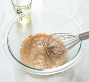 Vinaigrette ingredients being whisked in a bowl.